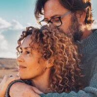 Young adult couple in love in outdoor leisure activity admiring travel destination. Contemplation. People traveler and adventure lifestyle. Man hug woman from behind. Looking away, togetherness two relationship counseling reno, nv with Cornelius Sheehan, LCSW. couple counseling clients embrace, outdoors. Therapy in Reno